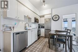 Kitchen with stainless steel appliances, tasteful backsplash, light wood-type flooring, and white cabinets - 