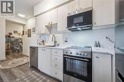 Kitchen with appliances with stainless steel finishes, tasteful backsplash, dark wood-type flooring, and light stone countertops - 