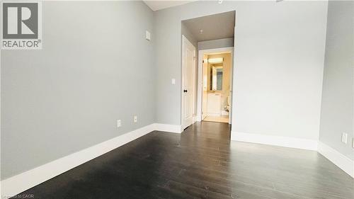 Empty room with baseboards and dark wood finished floors - 155 St. Leger Unit# 107, Kitchener, ON - Indoor Photo Showing Other Room