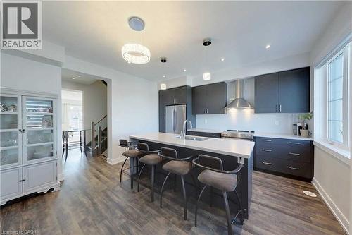 Kitchen featuring an island with sink, hanging light fixtures, a breakfast bar area, stainless steel appliances, and wall chimney exhaust hood - 588 Rapids Lane, Mississauga, ON - Indoor Photo Showing Kitchen With Stainless Steel Kitchen With Upgraded Kitchen