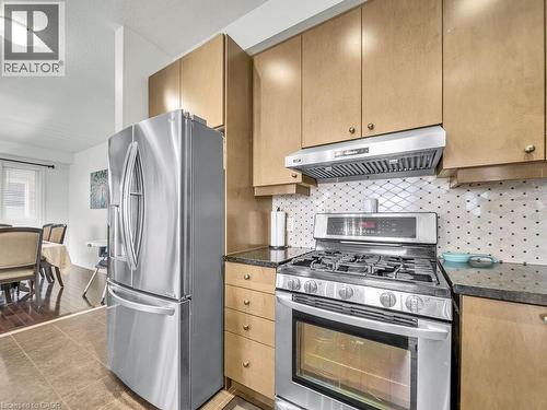 Kitchen featuring stainless steel appliances, under cabinet range hood, tasteful backsplash, and dark tile patterned floors - 3 Creighton Avenue, Guelph, ON - Indoor Photo Showing Kitchen
