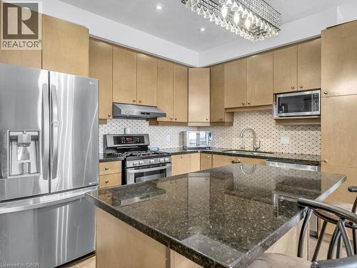 Kitchen with stainless steel appliances, dark stone counters, light brown cabinets, backsplash, and under cabinet range hood - 3 Creighton Avenue, Guelph, ON - Indoor Photo Showing Kitchen With Upgraded Kitchen