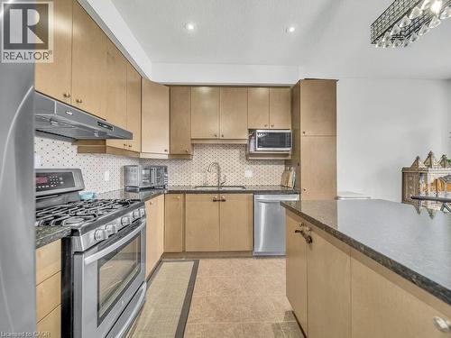 Kitchen featuring stainless steel appliances, tasteful backsplash, under cabinet range hood, dark stone countertops, and light tile patterned flooring - 3 Creighton Avenue, Guelph, ON - Indoor Photo Showing Kitchen With Upgraded Kitchen