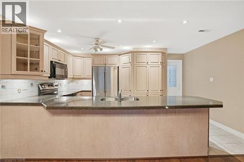 Kitchen with glass insert cabinets, stainless steel appliances, tasteful backsplash, a peninsula, and ceiling fan - 3230 New Street Unit# 7, Burlington, ON - Indoor Photo Showing Kitchen With Double Sink
