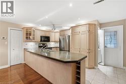 Kitchen with glass insert cabinets, open shelves, a peninsula, dark stone countertops, and appliances with stainless steel finishes - 