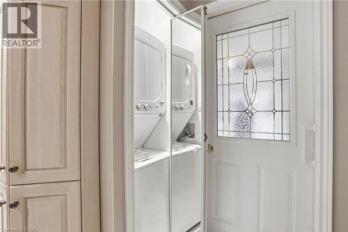 Laundry room with stacked washing machine and dryer at garage entry - 3230 New Street Unit# 7, Burlington, ON - Indoor Photo Showing Laundry Room