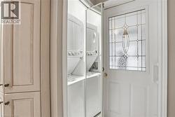 Laundry room with stacked washing machine and dryer at garage entry - 