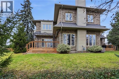 Rear view of property featuring a wooden deck, a chimney, a lawn, and brick siding - 3230 New Street Unit# 7, Burlington, ON - Outdoor With Deck Patio Veranda
