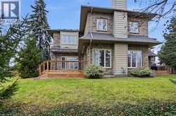 Rear view of property featuring a wooden deck, a chimney, a lawn, and brick siding - 