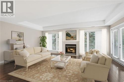 Virtually stagedLiving room with a glass covered fireplace, wood finished floors, and a tray ceiling - 3230 New Street Unit# 7, Burlington, ON - Indoor Photo Showing Living Room With Fireplace