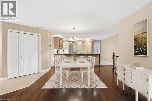 Virtually staged Dining area with a chandelier and dark wood-style floors - 3230 New Street Unit# 7, Burlington, ON - Indoor Photo Showing Dining Room