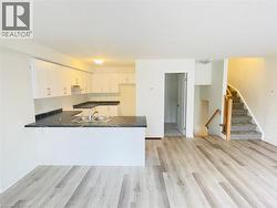 Kitchen featuring dark countertops, white cabinets, a peninsula, and light wood-style floors - 