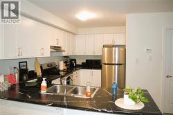 Kitchen featuring white cabinets, stainless steel appliances, under cabinet range hood, and a peninsula - 