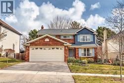 Traditional home with asphalt driveway, a chimney, a garage, board and batten siding, and brick siding - 
