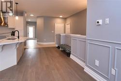 Kitchen with pendant lighting, white cabinetry, a kitchen breakfast bar, wall chimney range hood, and light wood-type flooring - 