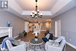 Living room with dark wood-type flooring, a tray ceiling, a chandelier, and sink - 