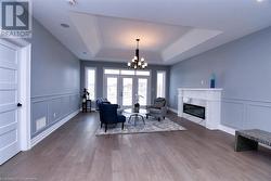 Living room with hardwood / wood-style flooring, an inviting chandelier, and a tray ceiling - 