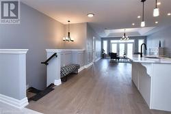 Kitchen featuring sink, a chandelier, hanging light fixtures, a tray ceiling, and french doors - 