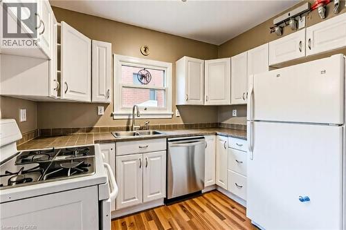 Kitchen featuring white appliances, white cabinets, and light wood-style floors - 172 Markland Street, Hamilton, ON - Indoor Photo Showing Kitchen With Double Sink