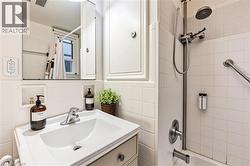 Bathroom featuring vanity, shower / tub combo with curtain, tile walls, and decorative backsplash - 