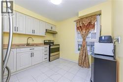 Kitchen featuring appliances with stainless steel finishes, under cabinet range hood, white cabinets, light countertops, and light tile patterned floors - 