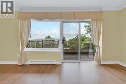 Doorway featuring wood finished floors, baseboard heating, and crown molding - 