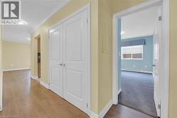 Corridor with crown molding, light wood-style flooring, baseboard heating, and light colored carpet - 