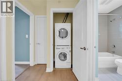 Laundry area with stacked washer / dryer and wood finished floors and linen closet. - 