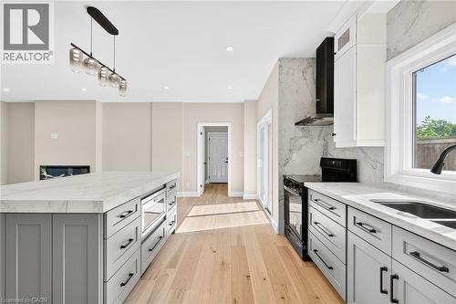 Kitchen featuring gray cabinetry, light stone countertops, hanging light fixtures, black electric range oven, and wall chimney range hood - 4006 Flemish Drive, Burlington, ON - Indoor Photo Showing Kitchen