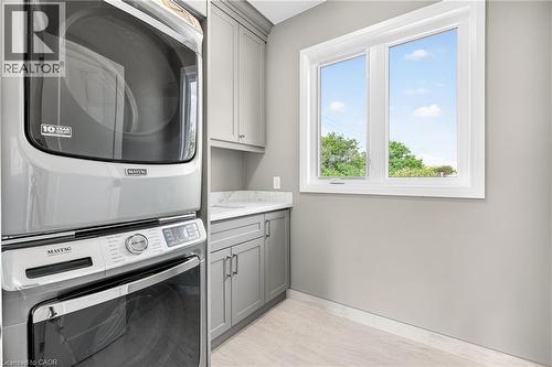 Laundry room featuring estacked washer and dryer and cabinet space - 4006 Flemish Drive, Burlington, ON - Indoor Photo Showing Laundry Room