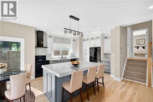 Kitchen with light stone counters, hanging light fixtures, black appliances, light wood-type flooring, and a kitchen island - 4006 Flemish Drive, Burlington, ON - Indoor Photo Showing Dining Room