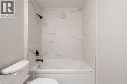 Full bathroom with tiled shower / bath, vanity, and toilet - 