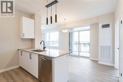 Kitchen featuring white cabinetry, decorative light fixtures, dishwasher, and kitchen peninsula - 