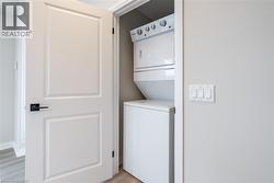 Laundry room with stacked washer and dryer and light wood-type flooring - 