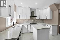 Kitchen with a center island, white cabinets, wall chimney range hood, modern cabinets, and recessed lighting - 
