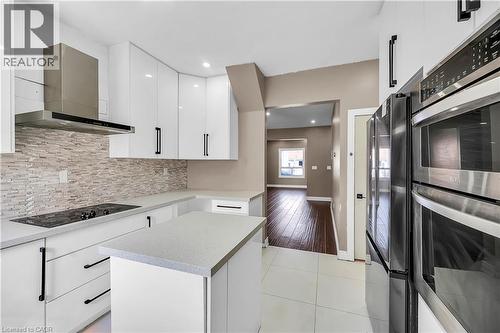 Kitchen featuring black appliances, white cabinets, wall chimney exhaust hood, light tile patterned flooring, and a kitchen island - 334 Cannon Street E, Hamilton, ON - Indoor Photo Showing Kitchen With Upgraded Kitchen