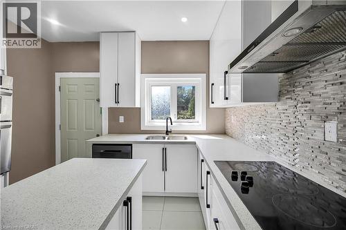 Kitchen with wall chimney exhaust hood, black electric cooktop, white cabinetry, dishwashing machine, and double oven - 334 Cannon Street E, Hamilton, ON - Indoor Photo Showing Kitchen With Double Sink