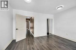 Unfurnished bedroom featuring dark wood-style flooring and baseboards - 