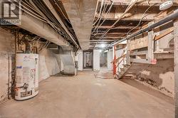 Unfinished basement with stairway, gas water heater, and heating unit - 
