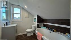 Full bathroom featuring lofted ceiling, wood finish floors, a garden tub, vanity, and tile walls - 