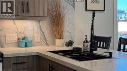 Kitchen featuring light stone counters, modern cabinets, and tasteful backsplash - 