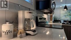 Kitchen view of black range with electric stovetop, recessed lighting, and decorative light fixtures - 