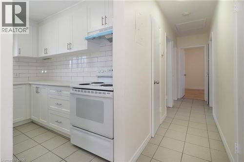Kitchen with white range with electric cooktop, white cabinets, light tile patterned floors, and tasteful backsplash - 24 Austin Drive, Waterloo, ON - Indoor Photo Showing Kitchen