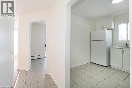 Kitchen with white cabinets, freestanding refrigerator, light countertops, a baseboard heating unit, and light tile patterned floors - 24 Austin Drive, Waterloo, ON - Indoor Photo Showing Kitchen