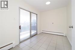 Unfurnished room with baseboard heating and light tile patterned flooring - 