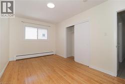 Unfurnished bedroom with a baseboard heating unit, light wood-style flooring, and a closet - 