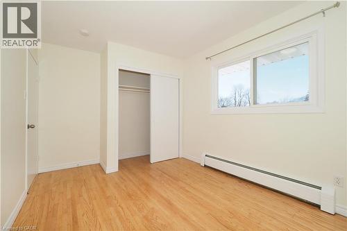 Unfurnished bedroom featuring a baseboard radiator, light wood-type flooring, and a closet - 24 Austin Drive, Waterloo, ON - Indoor Photo Showing Other Room
