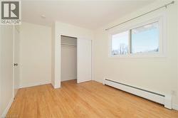 Unfurnished bedroom featuring a baseboard radiator, light wood-type flooring, and a closet - 
