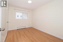 Empty room with a baseboard heating unit and light wood-style flooring - 