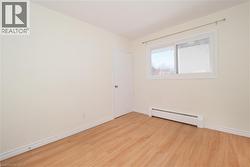 Empty room featuring a baseboard radiator and light wood finished floors - 